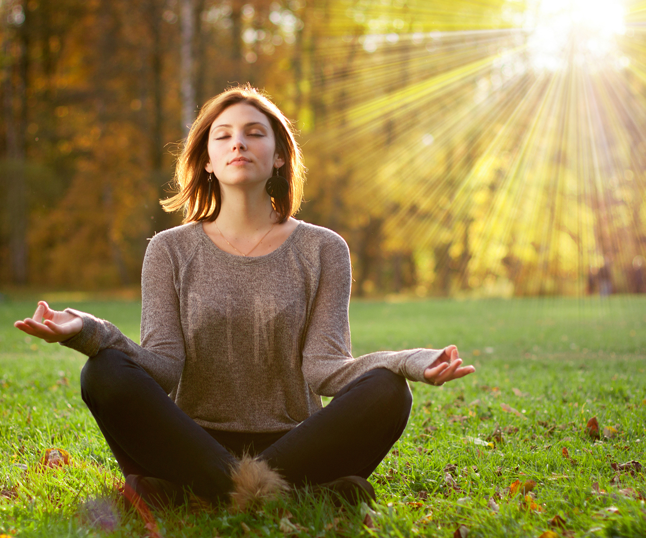 Beautiful young girl meditating in autumn park